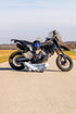 Supermotofahrer in Schneidersitz sitzend vor Supermoto mit Boobs Brille