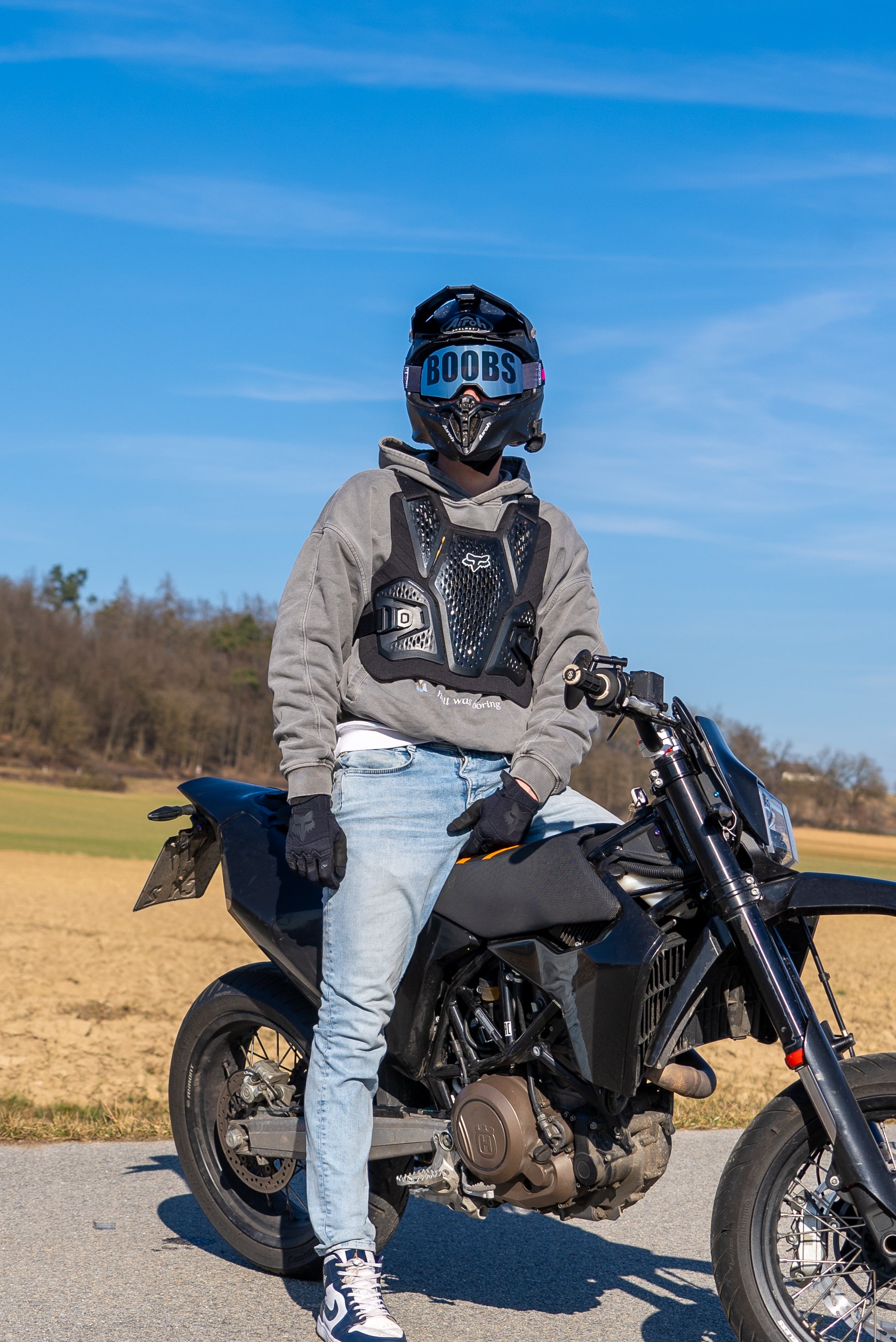 lässig auf Motorradsitzender Mann mit Boobs Brille